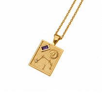 A gold pendant necklace featuring a zodiac design with a purple amethyst gemstone and a small clear stone, shown on a white background.