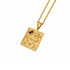 A gold pendant necklace featuring a square zodiac design with engraved stars, constellations, a flower motif, and a small dark red rectangular gemstone, shown on a white background.