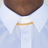 A cuban link chain under a white button up shirt collar, with soft lighting. 