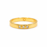 A gold vermeil ring featuring three lab grown diamonds bezel set, on a white background. 