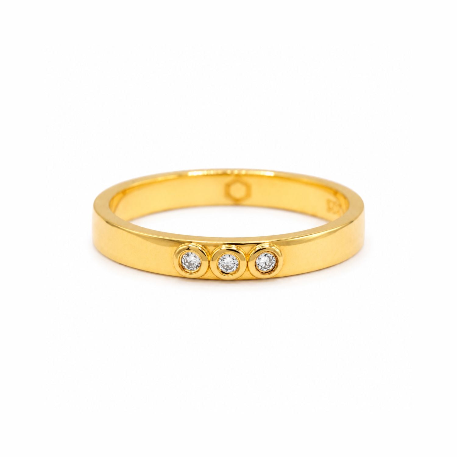 A gold vermeil ring featuring three lab grown diamonds bezel set, on a white background. 