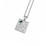 A silver-toned square pendant necklace featuring an engraved constellation design, Roman numeral III, and a small green rectangular inset, suspended from a matching silver chain against a plain white background.