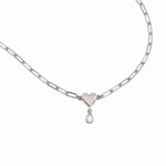 A silver paperclip chain necklace featuring a polished heart-shaped pendant with a small teardrop pearl charm below it, displayed on a clean white background.