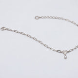 A silver paperclip chain bracelet with a small heart charm and teardrop pearl, displayed on a clean white background.