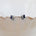 A pair of silver stud earrings with rectangular blue gemstones and small white pearl accents, displayed on the edge of a beige clam shell against a white background.