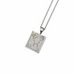 A silver pendant necklace featuring a rectangular shape, engraved details, a textured floral motif, and small clear gemstones, suspended from a delicate gold chain on a white background.