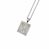 A silver pendant necklace featuring a rectangular shape, engraved details, a textured floral motif, and small clear gemstones, suspended from a delicate gold chain on a white background.