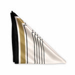 A folded silk scarf with a modern geometric pattern, featuring a white base with black vertical stripes, a gold stripe, and a solid black border, displayed on a clean white background.