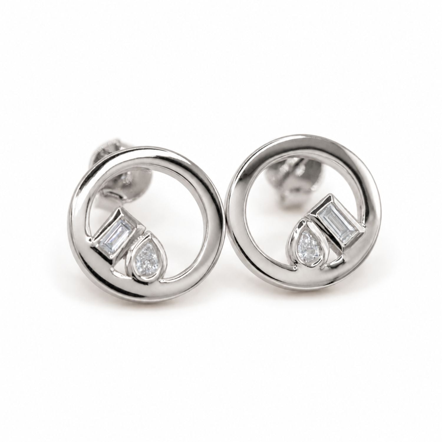 A pair of silver-toned stud earrings with open circular rings and small lab-grown baguette and pear-cut diamonds, shown on a plain white background.