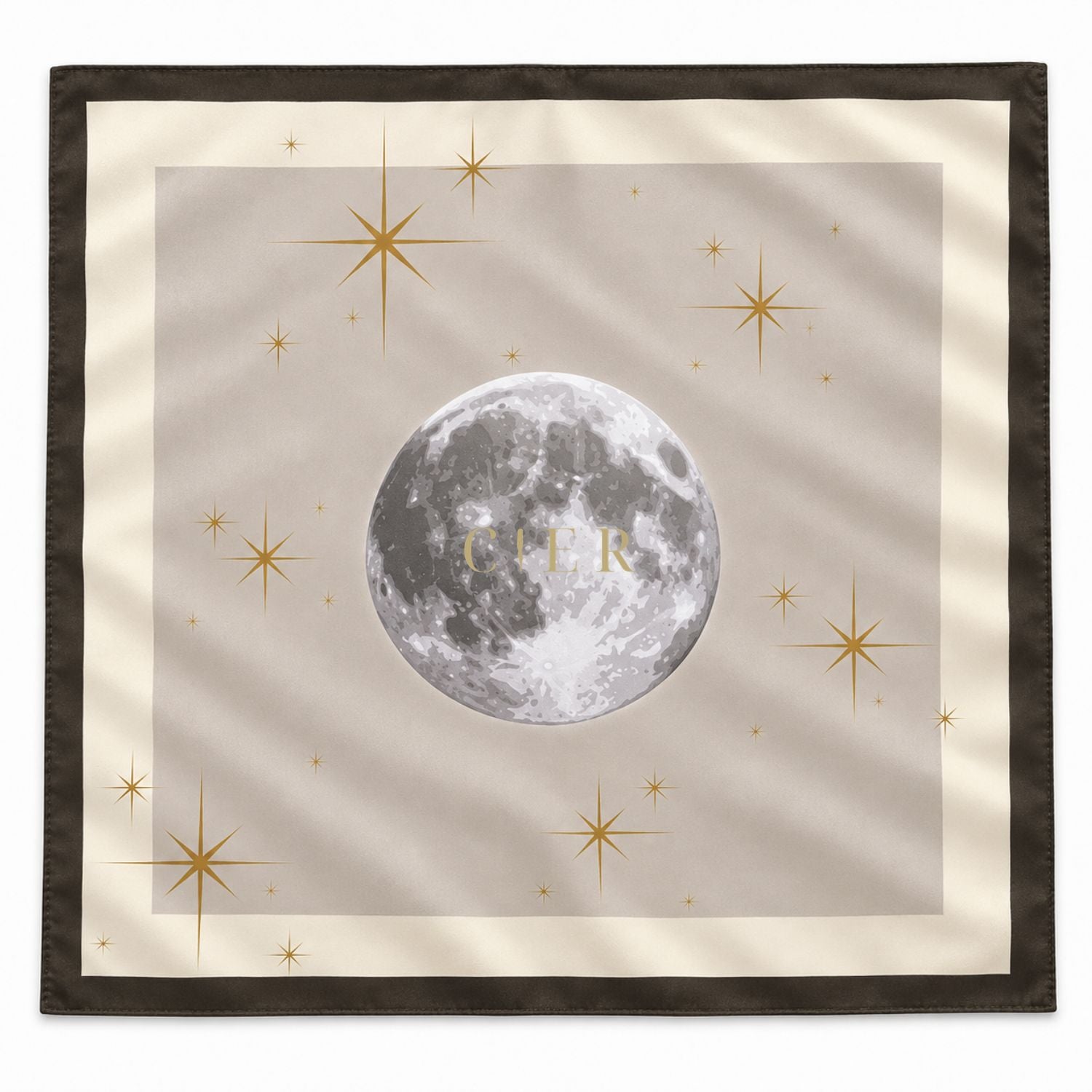 A square scarf with a celestial design, featuring a detailed gray moon at the center with the gold monogram 'CIER', surrounded by gold stars on a beige background with a dark brown border.