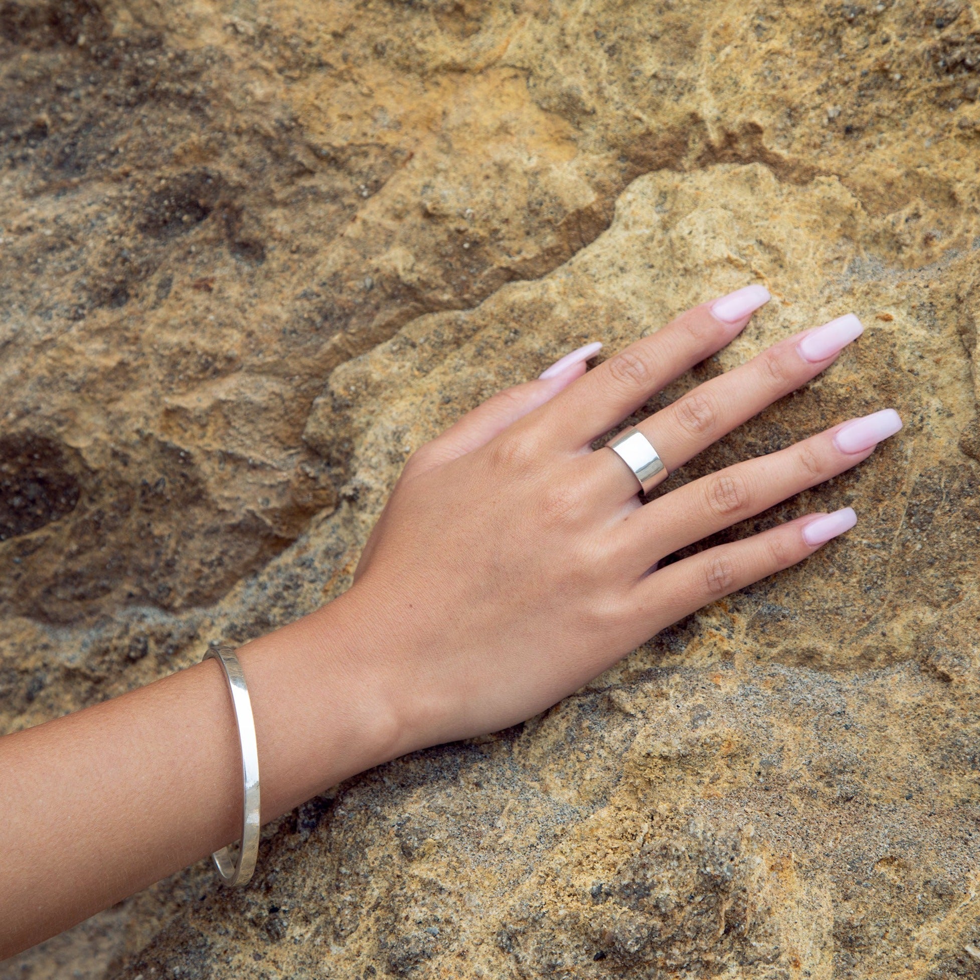 A person's hand displaying a sterling silver bangle from the Cyclical collection.