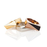 Three rectangular rings in gold, rose gold, and sterling silver stacked on a white background. 