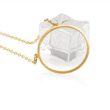 A 14K gold plated circular necklace con a piece of ice on white background shot in studio.