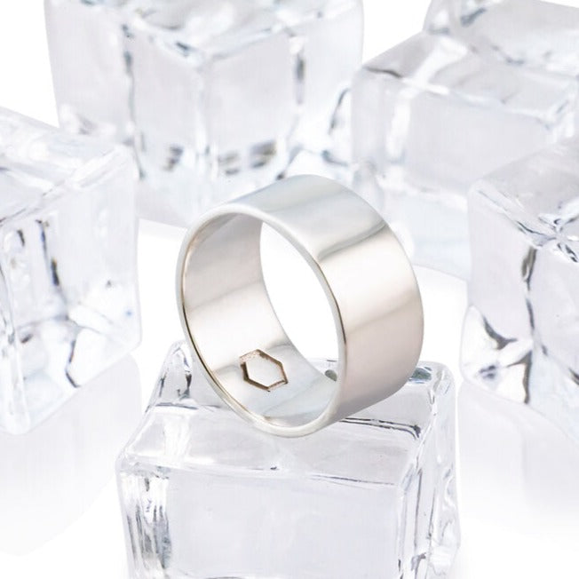 A cyclical thick ring made of sterling silver with a hexagonal center embellishment, displayed on a white background with ice cubes.