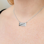 A sterling silver necklace pendant close up around a model's neck. 